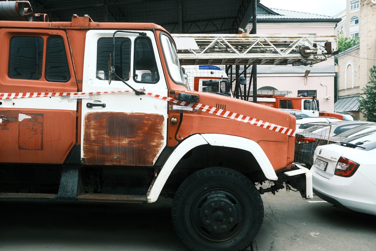 An old red and white ladder fire engine is parked among cars in a Moscow courtyard.