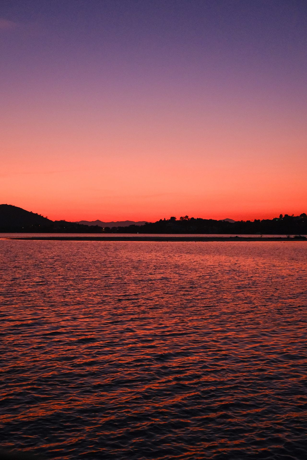 Vivid red and purple sunset reflected across rippling water near Plovdiv