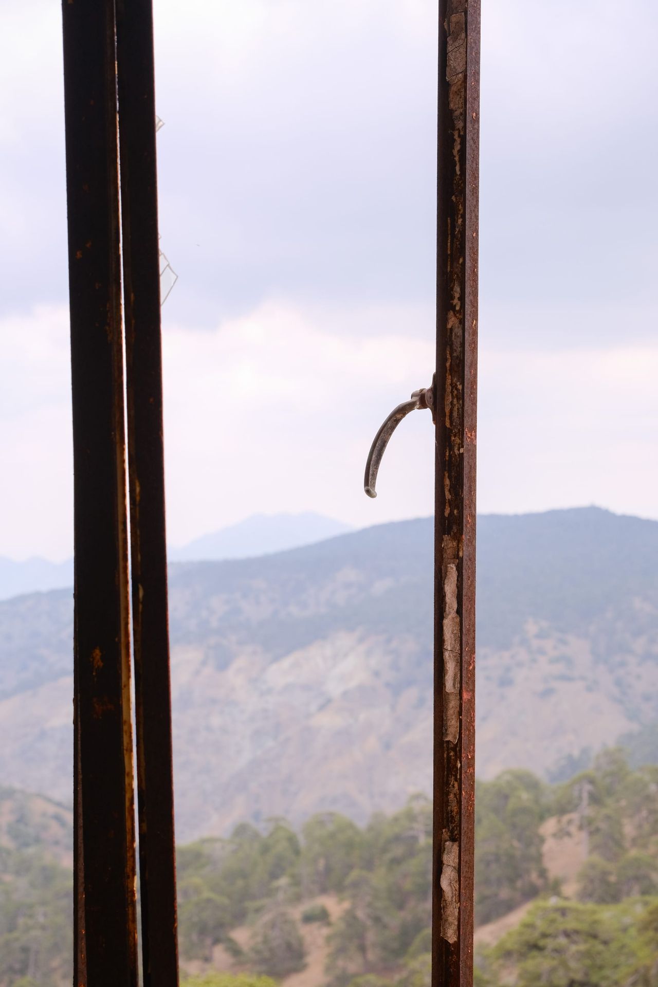Open weathered window framing hazy mountain ridges beneath a pale sky