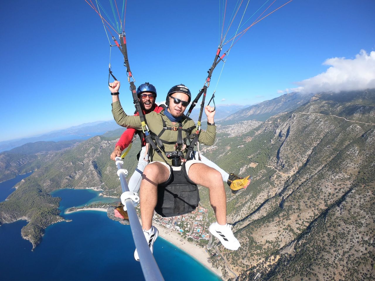 Paragliding passenger above the turquoise coast and steep mountains