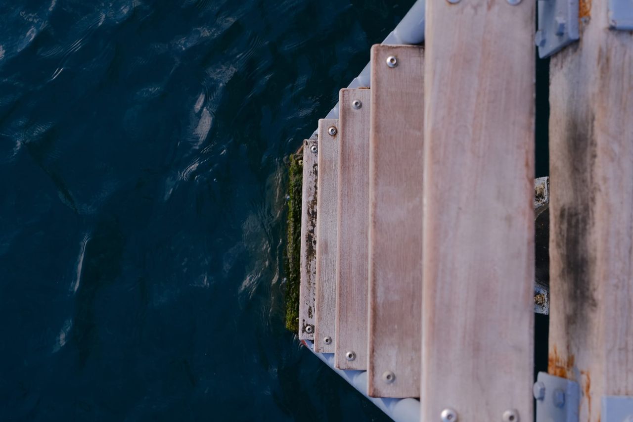 Dark water beside weathered wooden planks seen from above, Cyprus