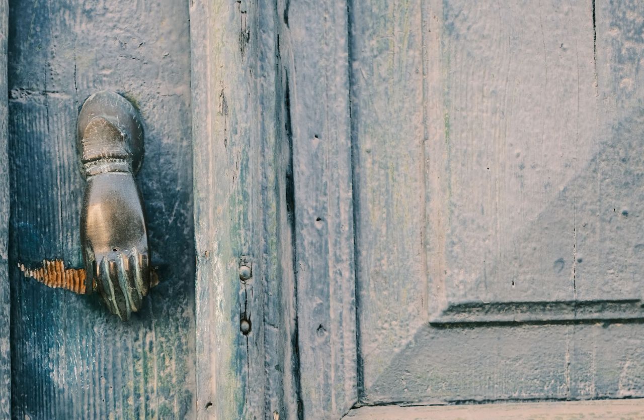 Hand-shaped metal knocker on a weathered blue wooden door, Cyprus