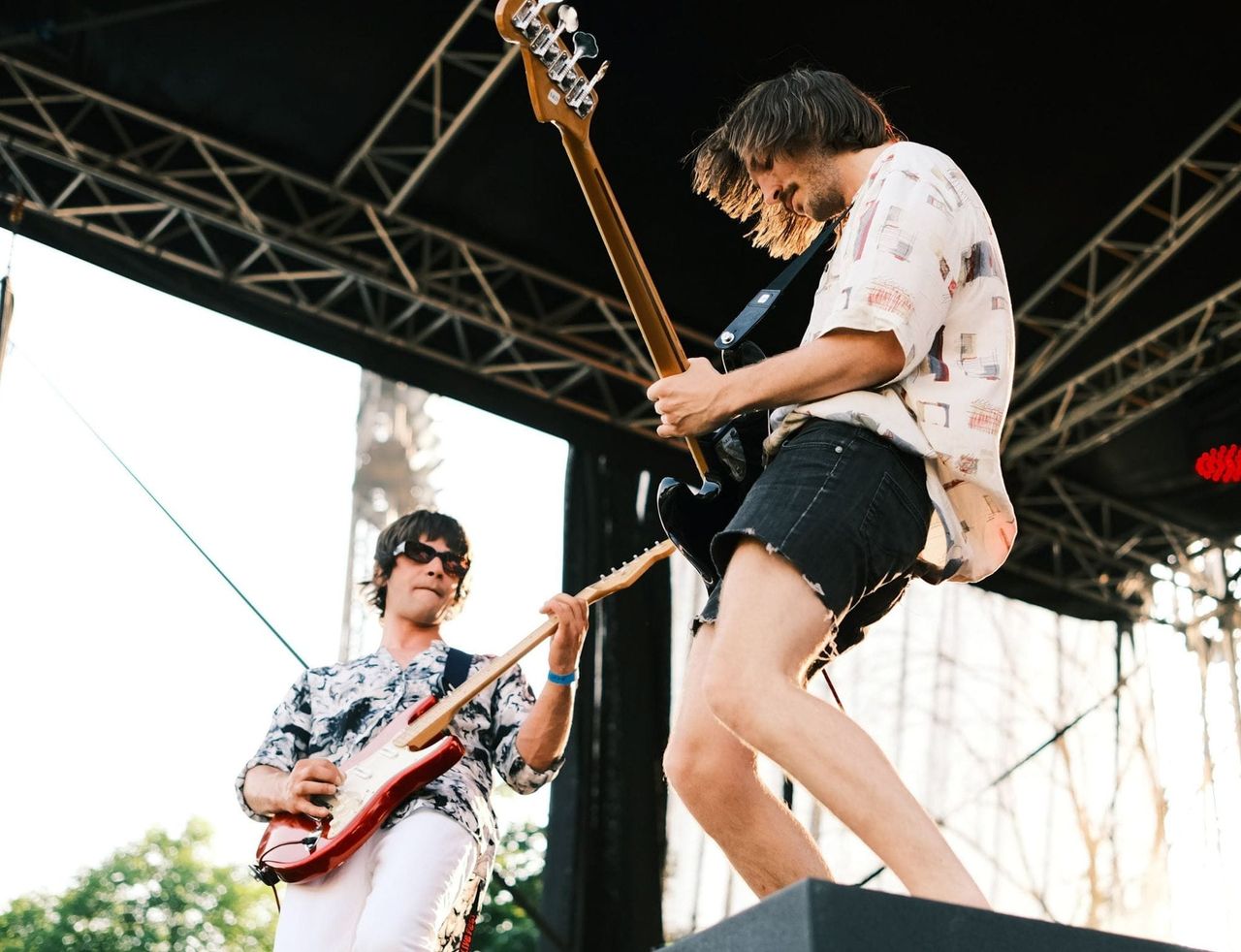 Two Love'n'Joy musicians playing bass and electric guitar on the outdoor festival stage.