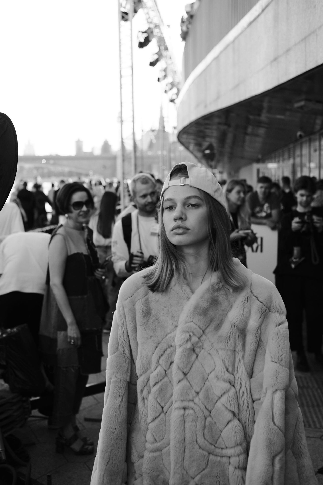 Black-and-white view of a model in a heavily textured jacket and a backward cap.