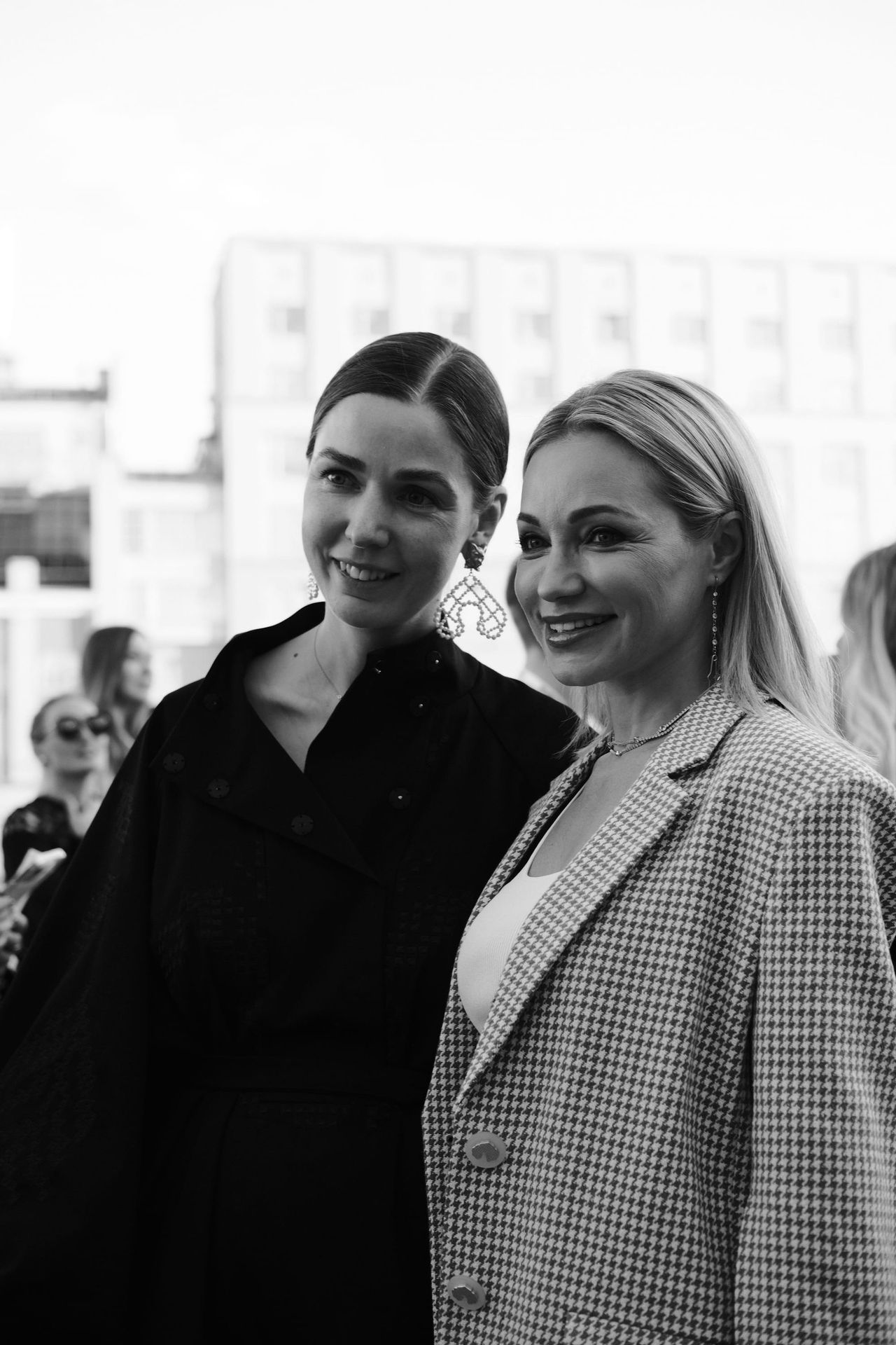Two women pose side by side outside the venue in a black-and-white portrait.
