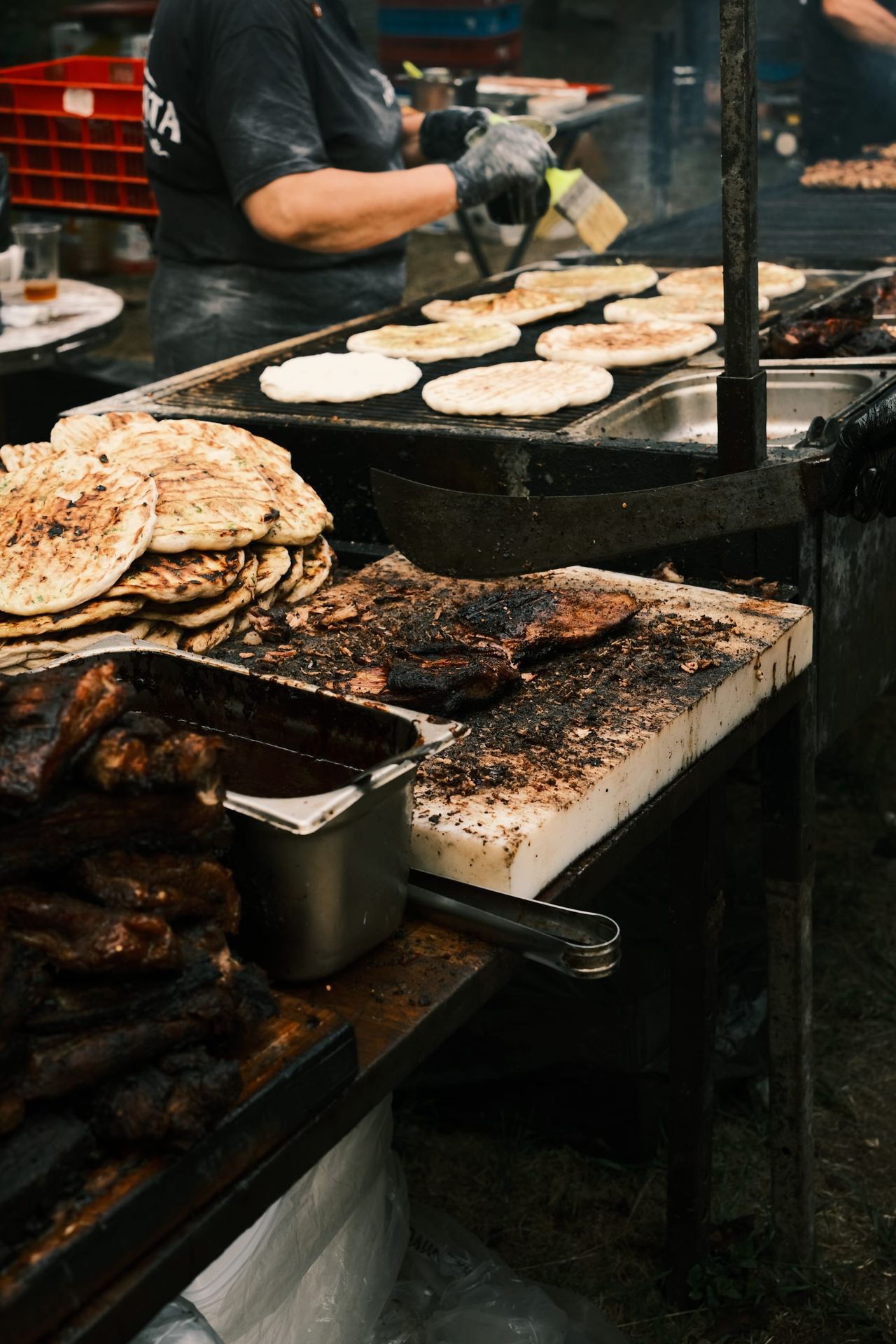 Flatbreads and grilled food fill the cooking surface of a busy festival stall.