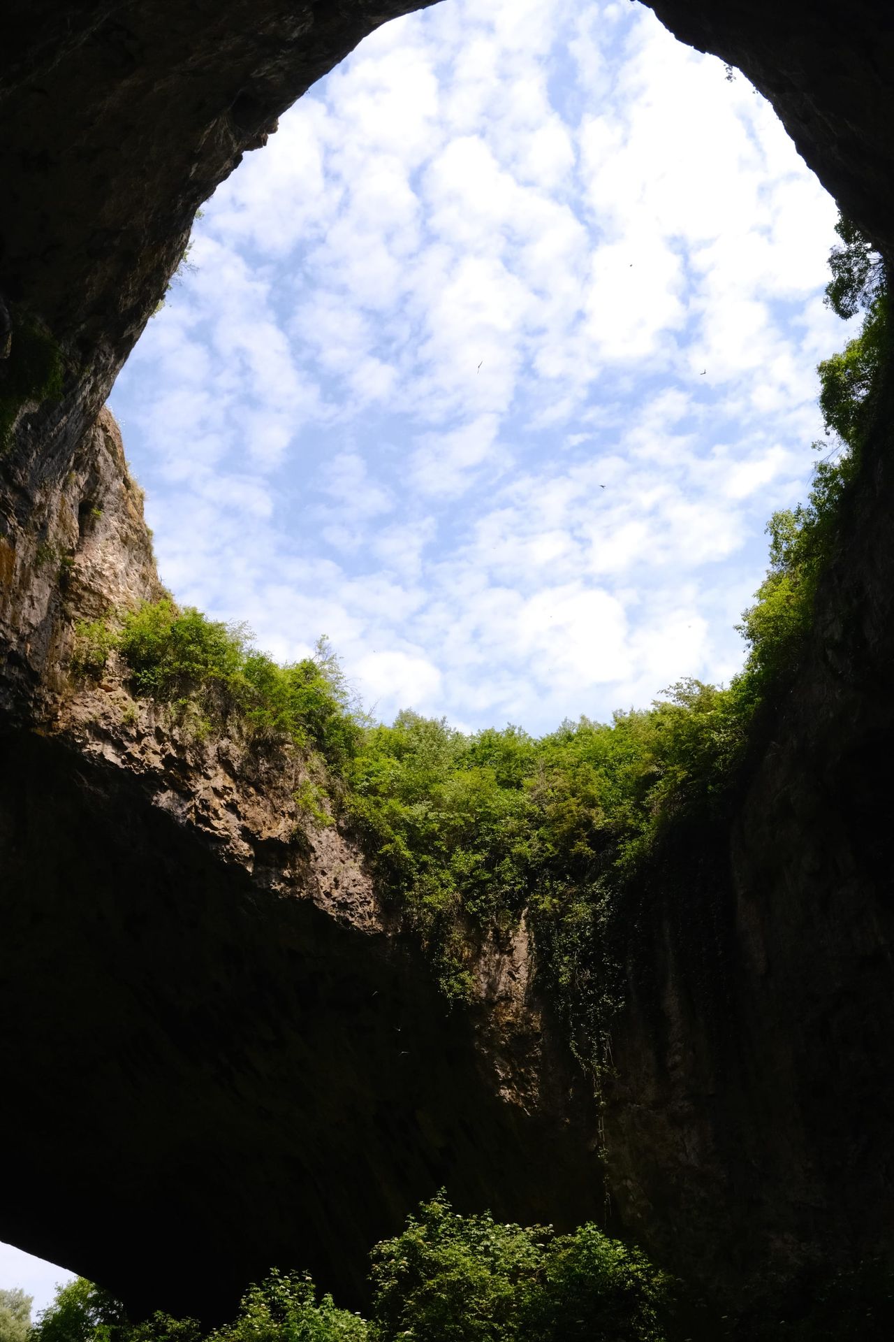 Blue sky and clouds visible through a cave skylight