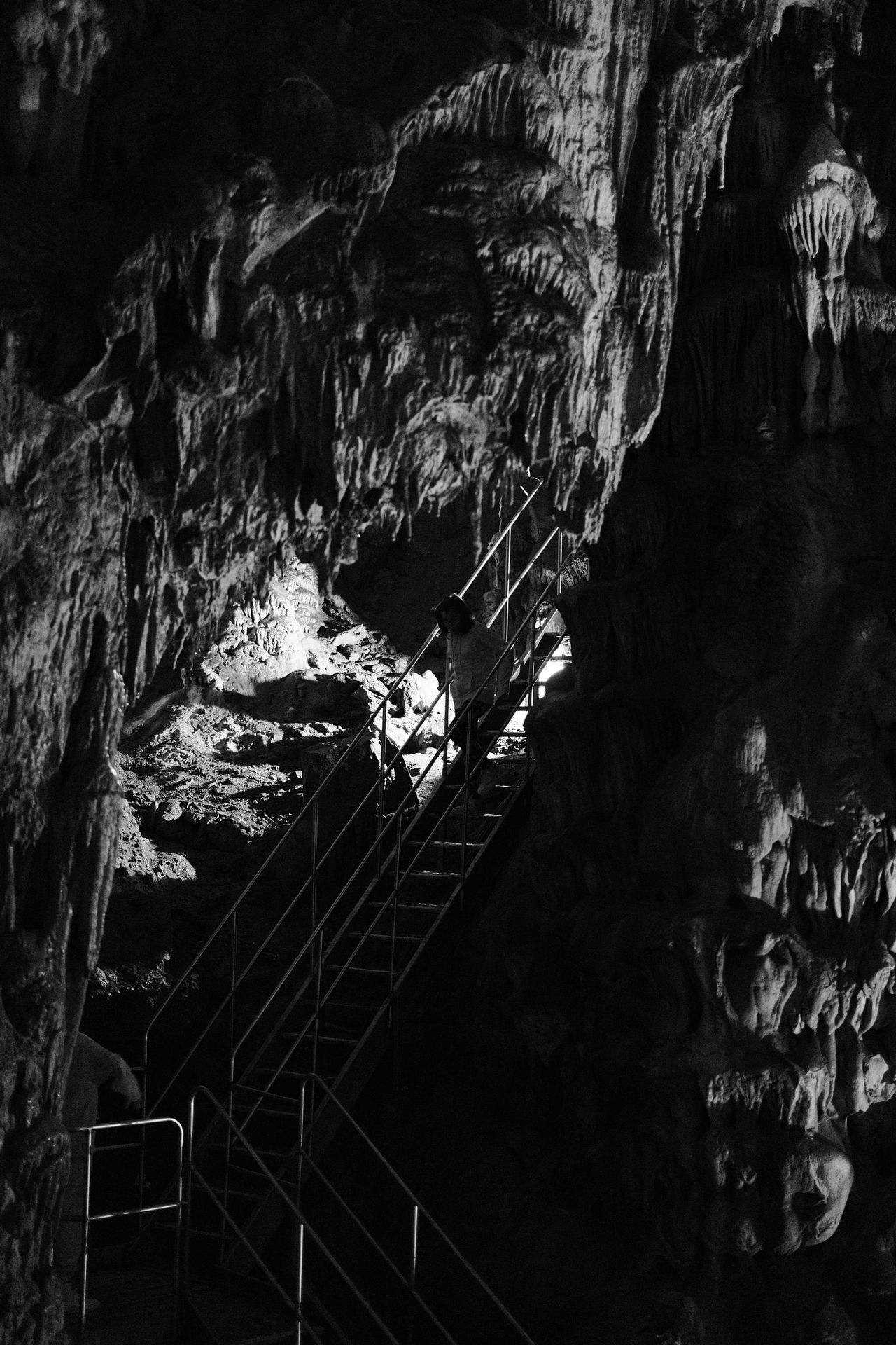 Illuminated cave formations surrounding a metal staircase