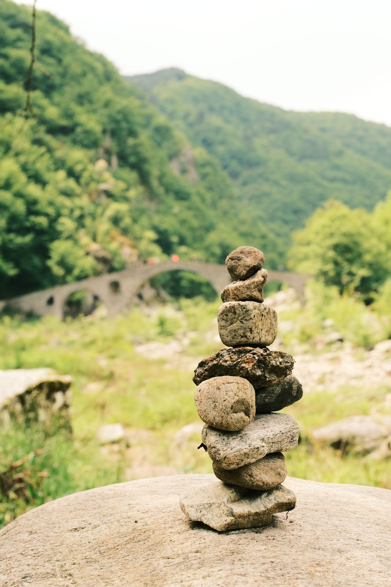 Stack of balanced stones with a bridge in the valley behind, Bulgaria