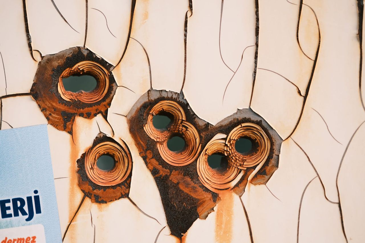 Bullet holes clustered in a heart-like shape on a metal sign