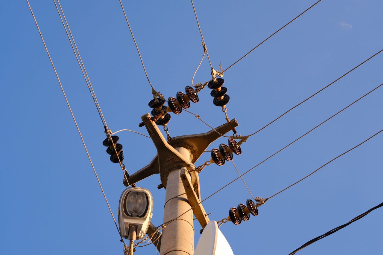 Power pole and overhead lines against a clear blue sky