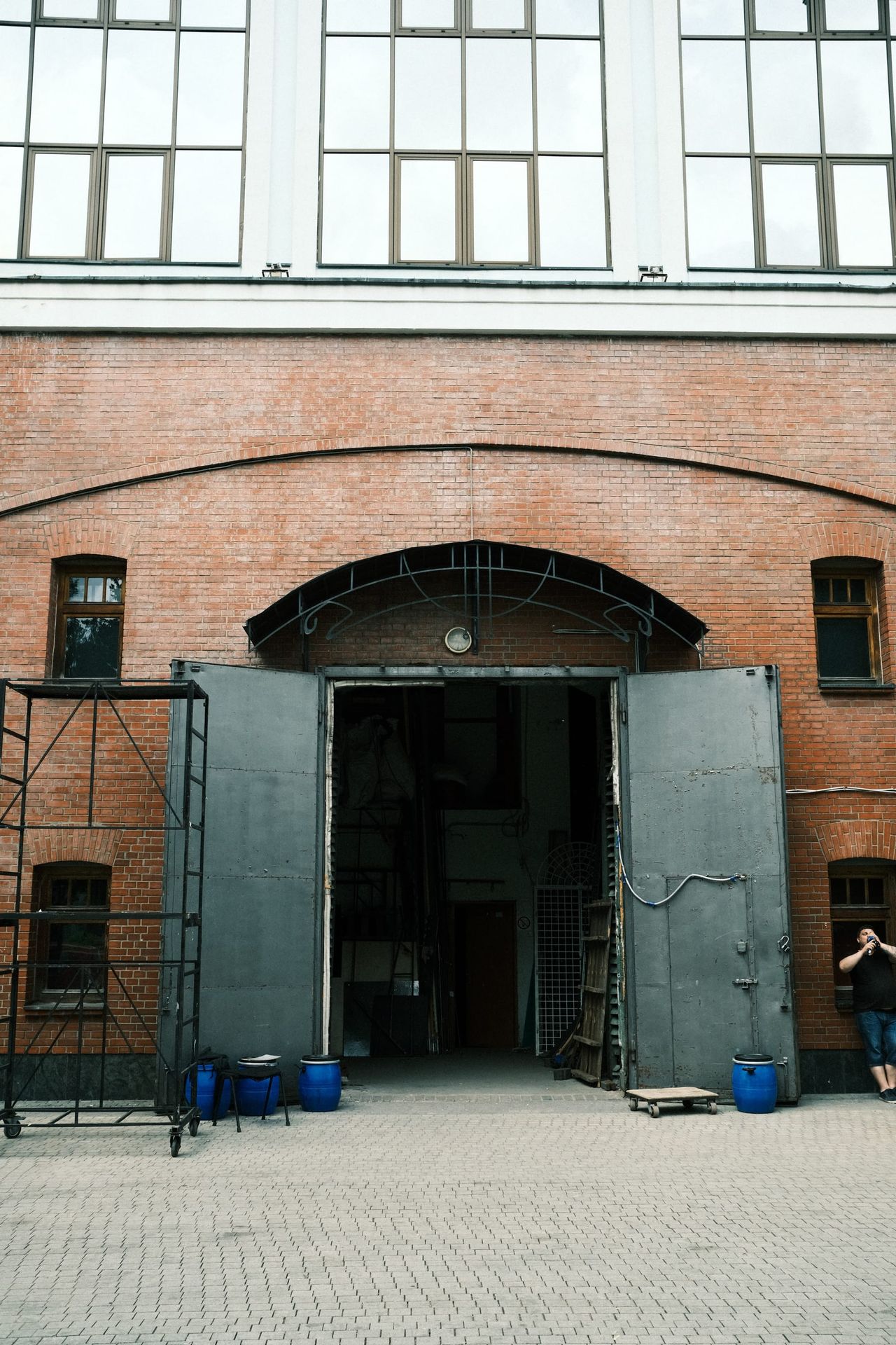 Open metal doors beneath an arched brick opening, with rows of tall windows above a Moscow courtyard.