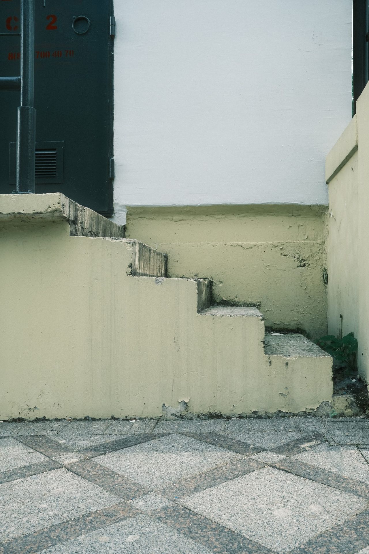A short concrete staircase rises beside a pale yellow wall above patterned pavement in Moscow.