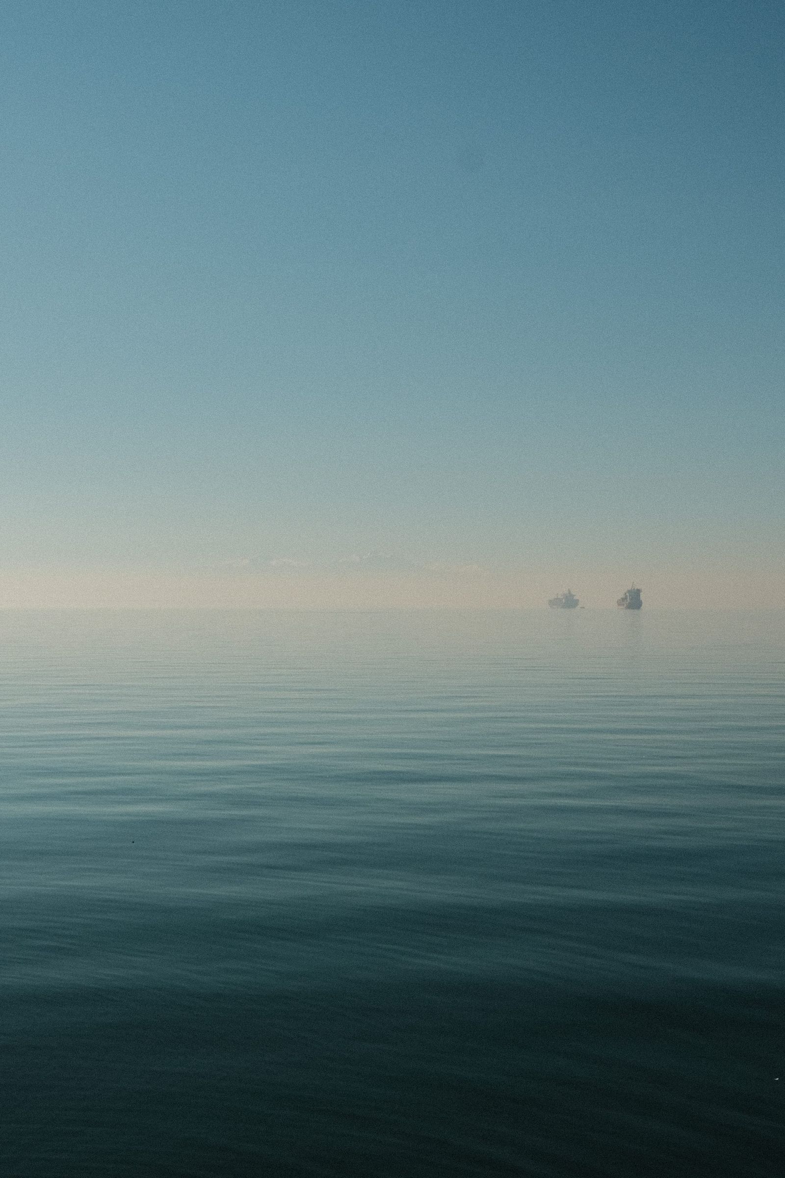 Calm Greek sea fading into a hazy blue horizon with two distant rocky islets