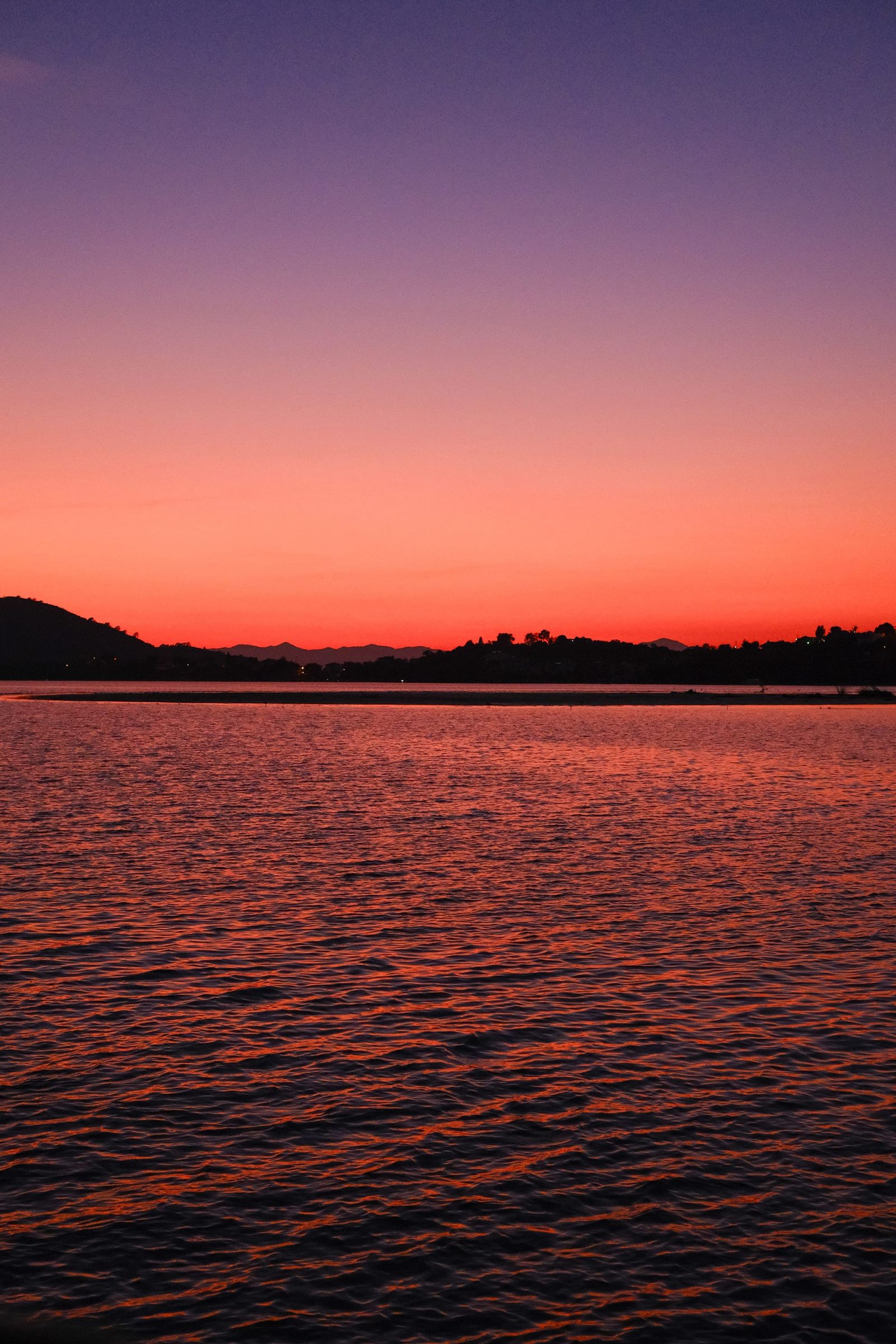 Vivid red and purple sunset reflected across rippling water near Plovdiv