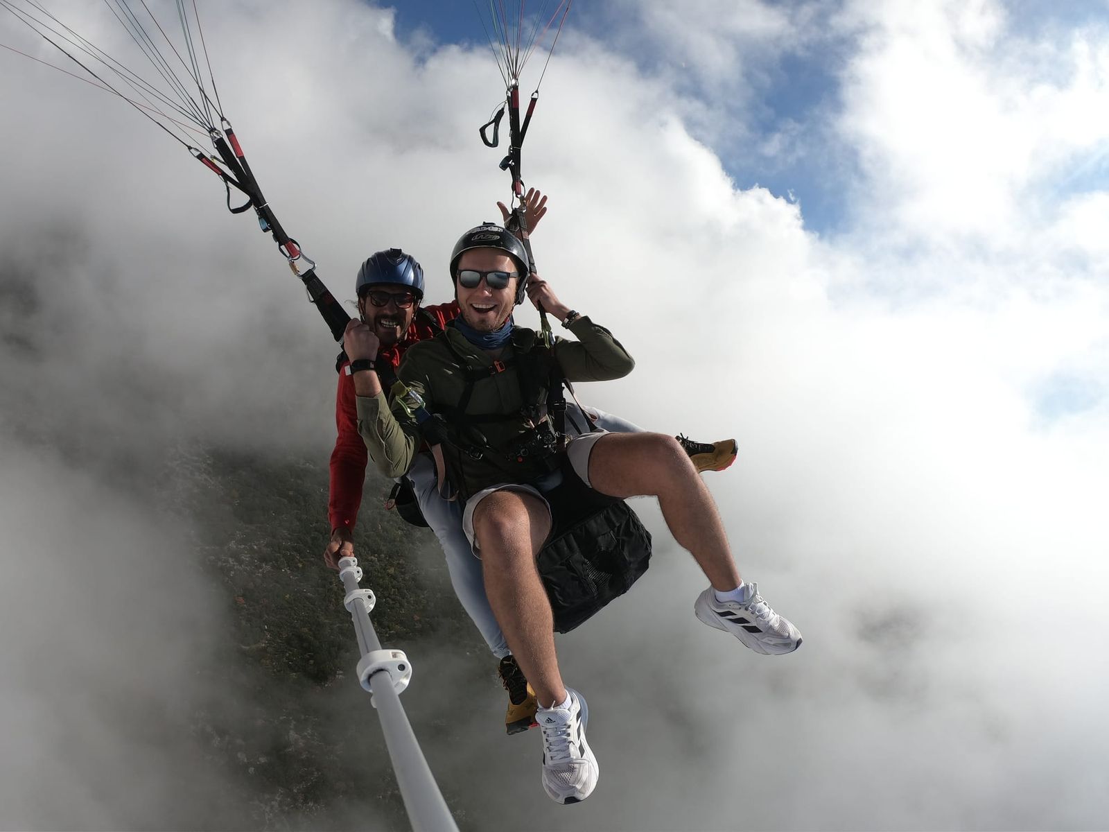 Passenger and tandem pilot flying beside a bank of white cloud