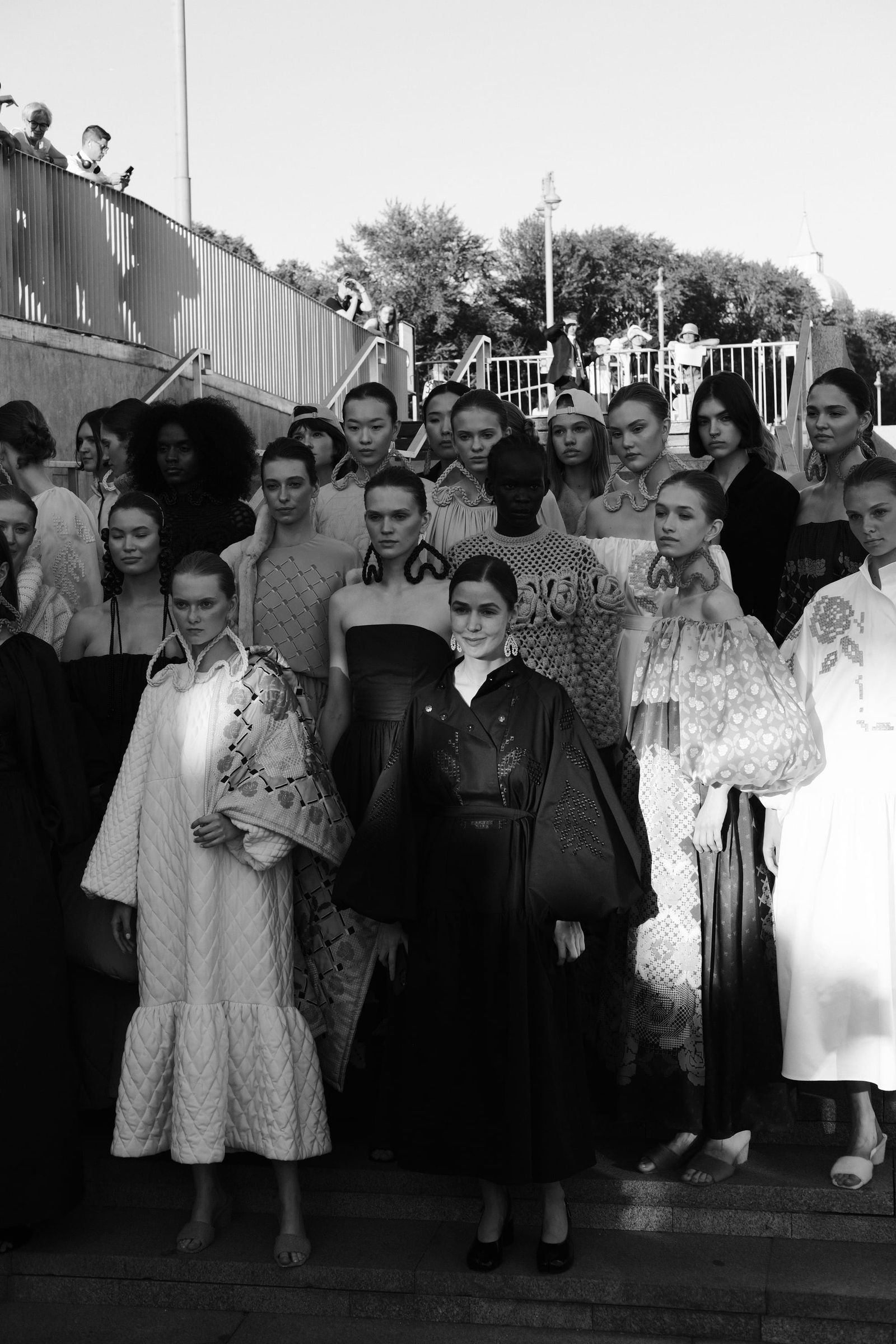 Black-and-white view of a large group of models arranged on outdoor steps.
