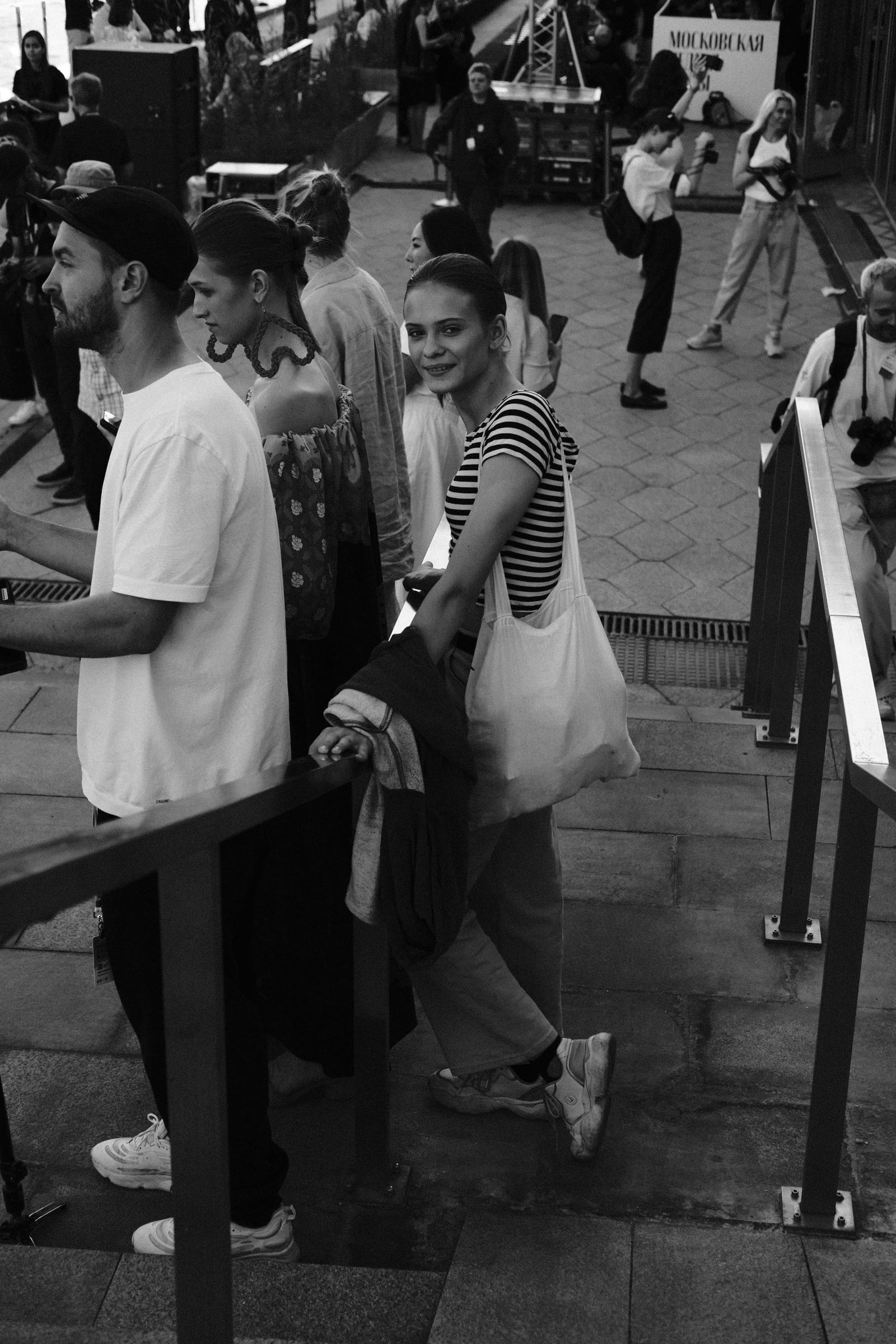 Guests gather along a narrow outdoor passage beside the venue in black and white.
