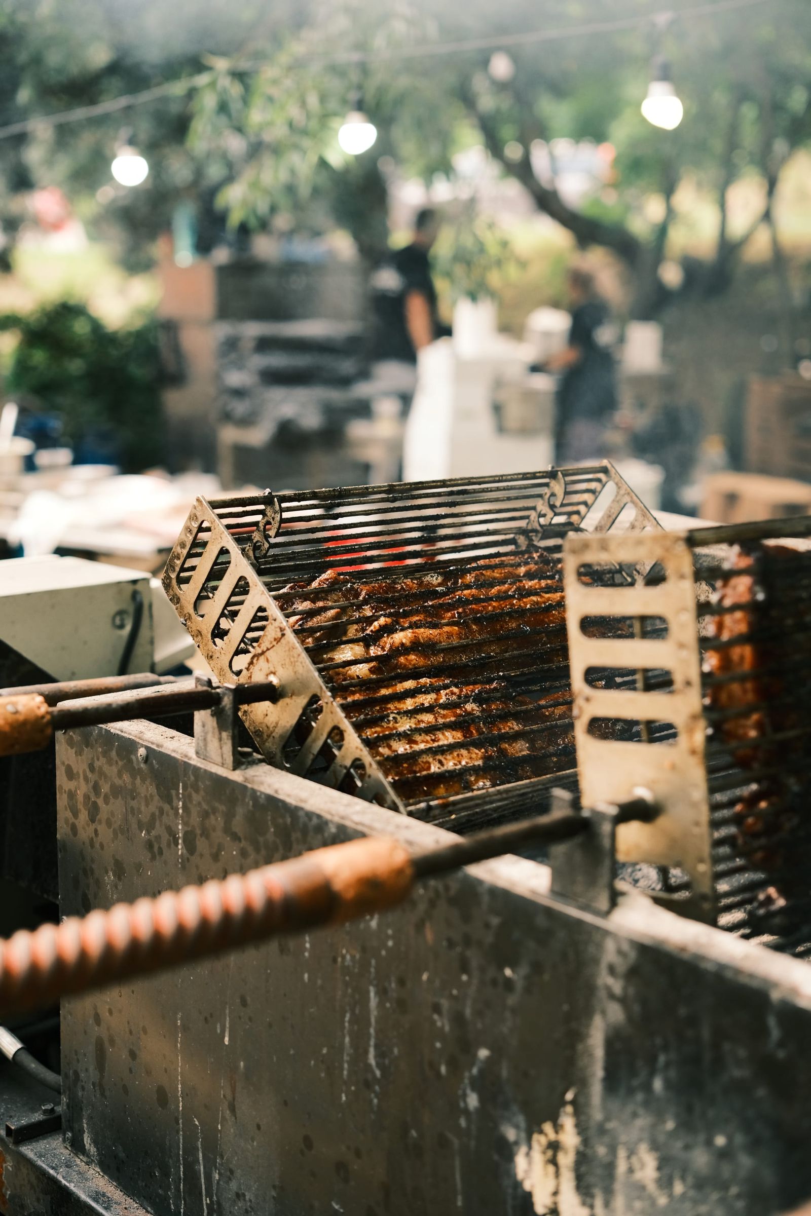 Close view of a grill basket and barbecue equipment at an outdoor food stall.