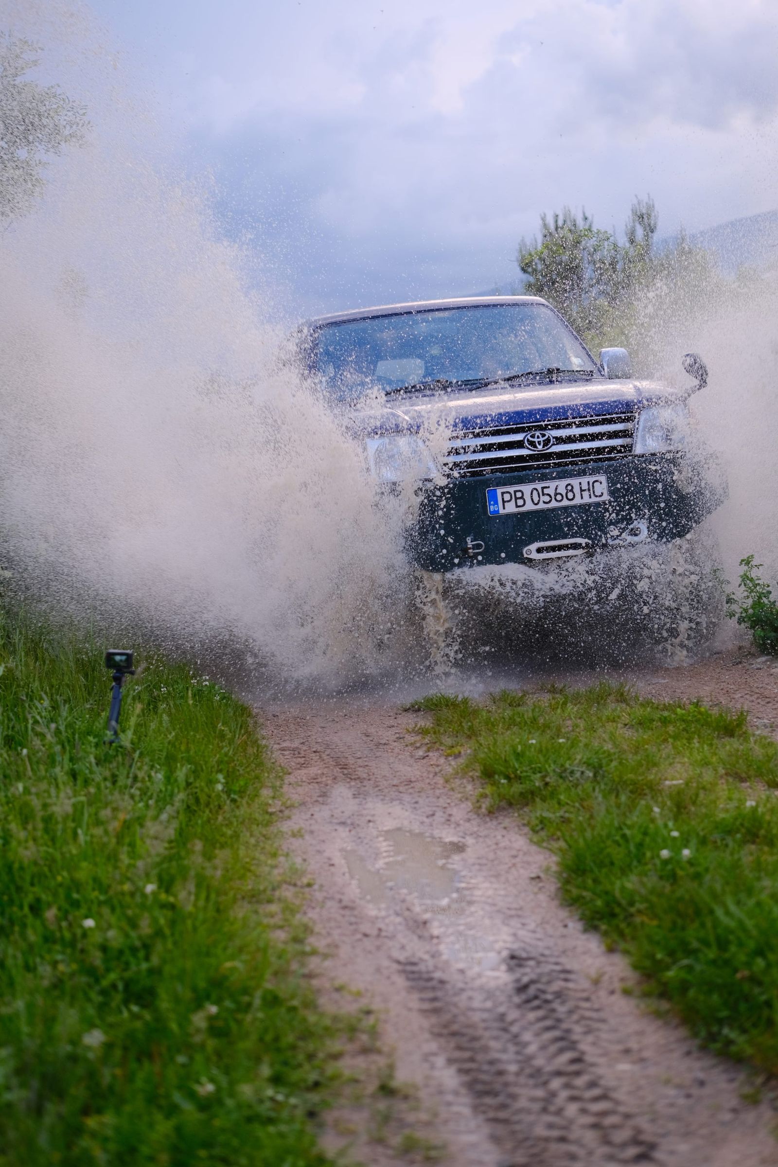 Four-wheel-drive vehicle throwing up water as it enters the puddle