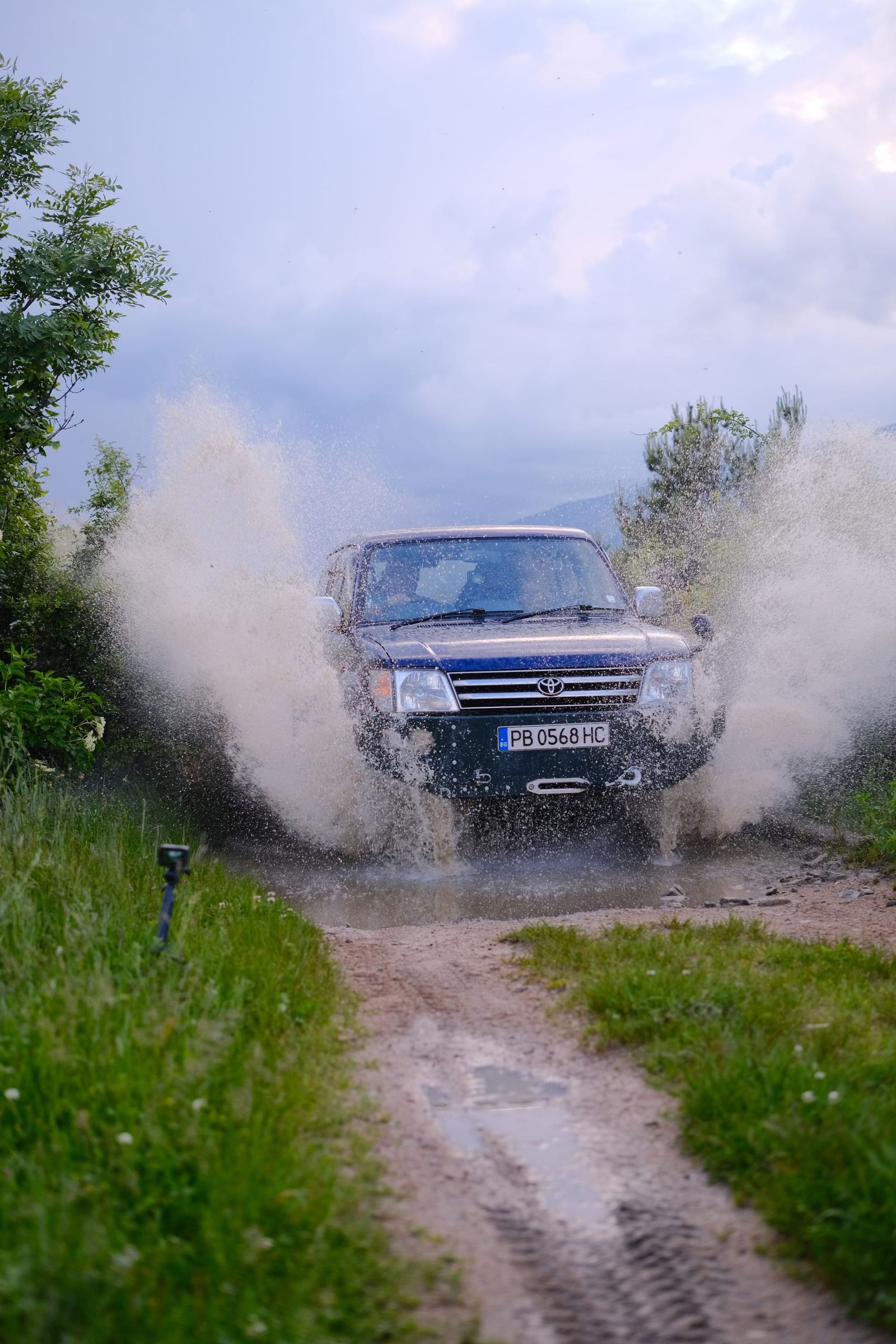 Front view of the vehicle emerging through a wall of spray