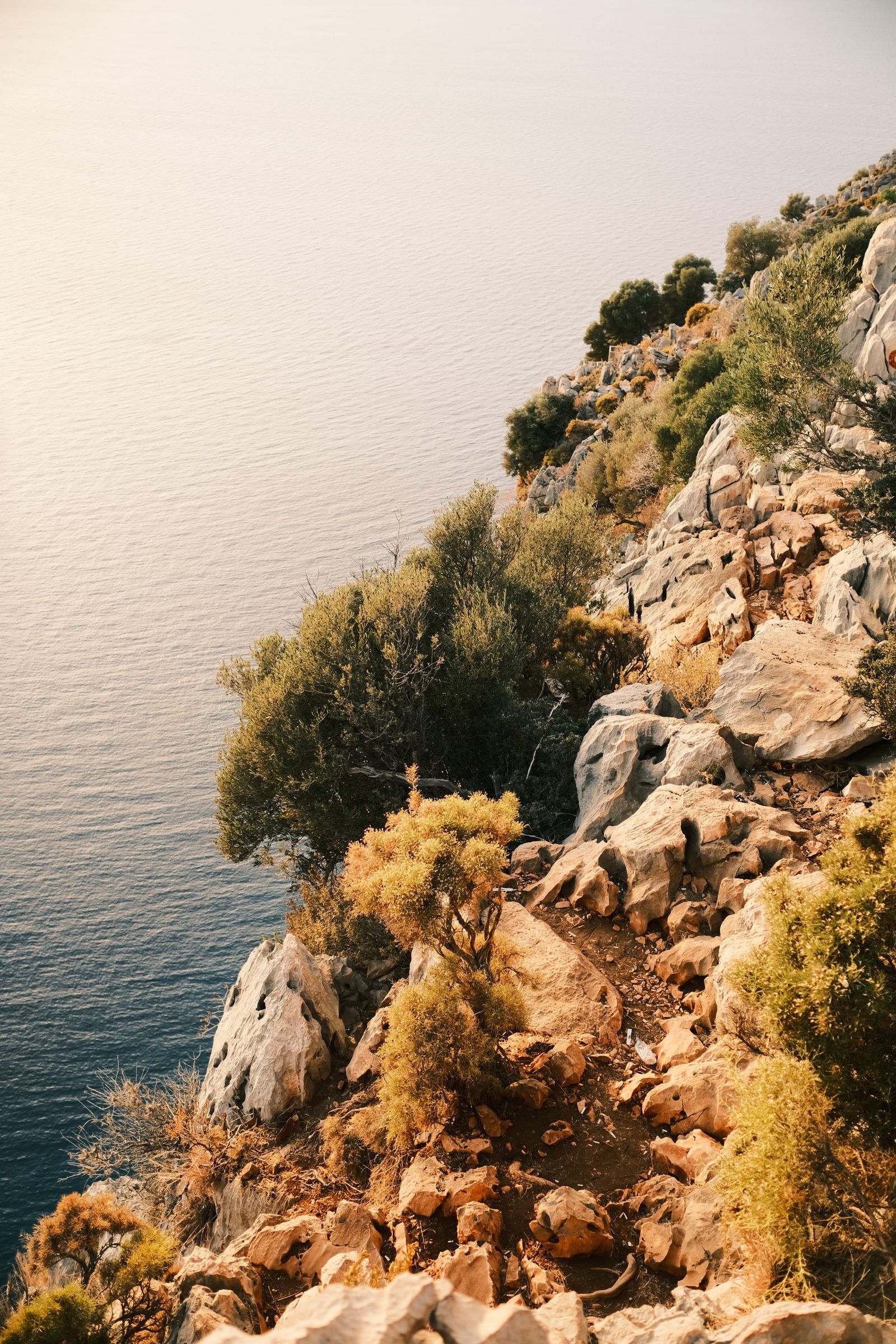Rocky Mediterranean cliff descending into calm blue water near Butterfly Valley