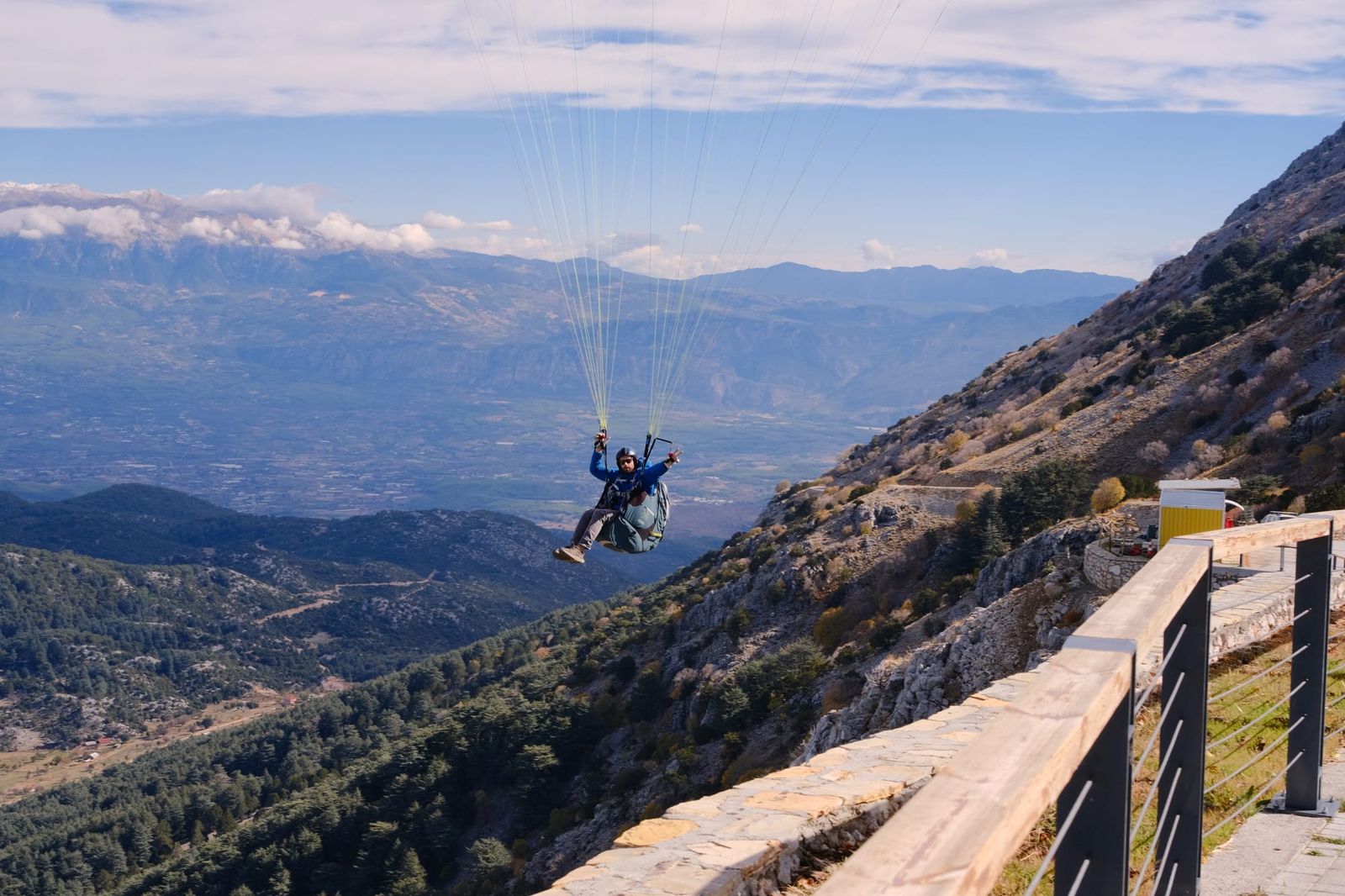 Tandem paraglider airborne beside Babadağ with mountains behind