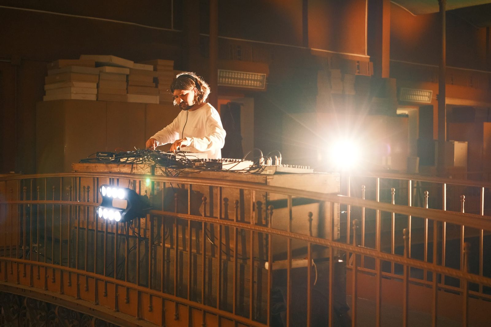 A person works behind a railing in a dim museum room, illuminated by a bright lamp.