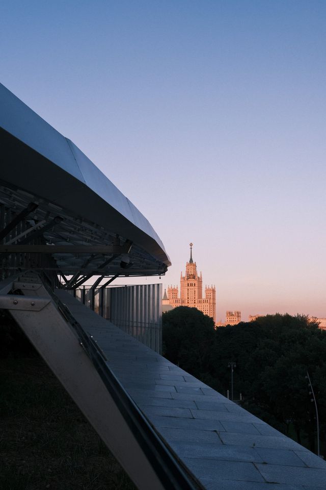 Modern bridge structure framing a distant Moscow high-rise at pastel dusk