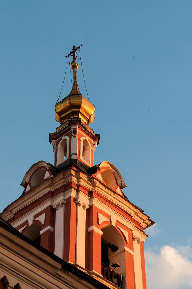 Red-and-white church bell tower glowing in warm light against a clear blue sky