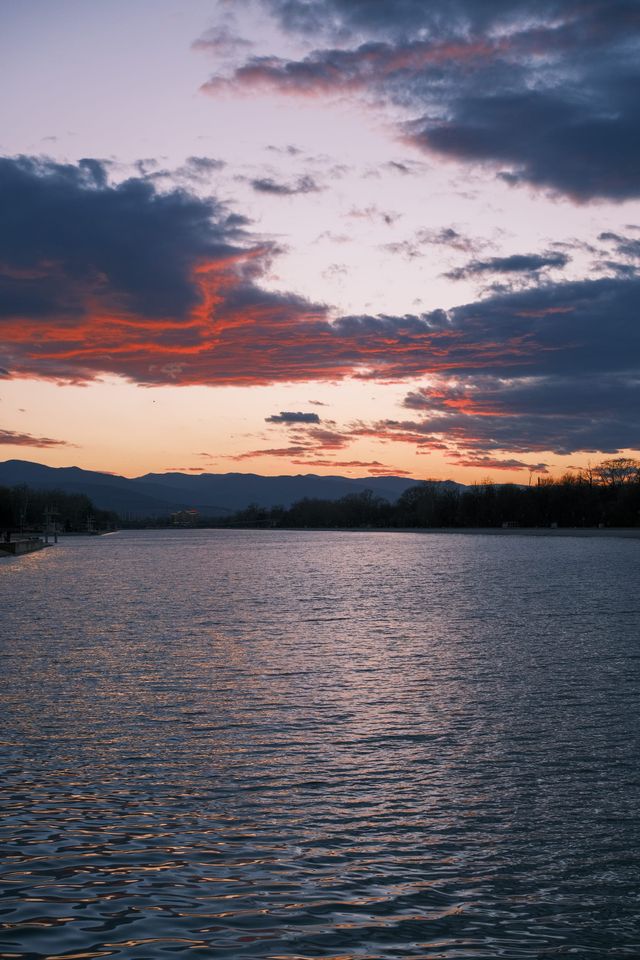 Red-edged storm clouds over a lake and distant hills at sunset
