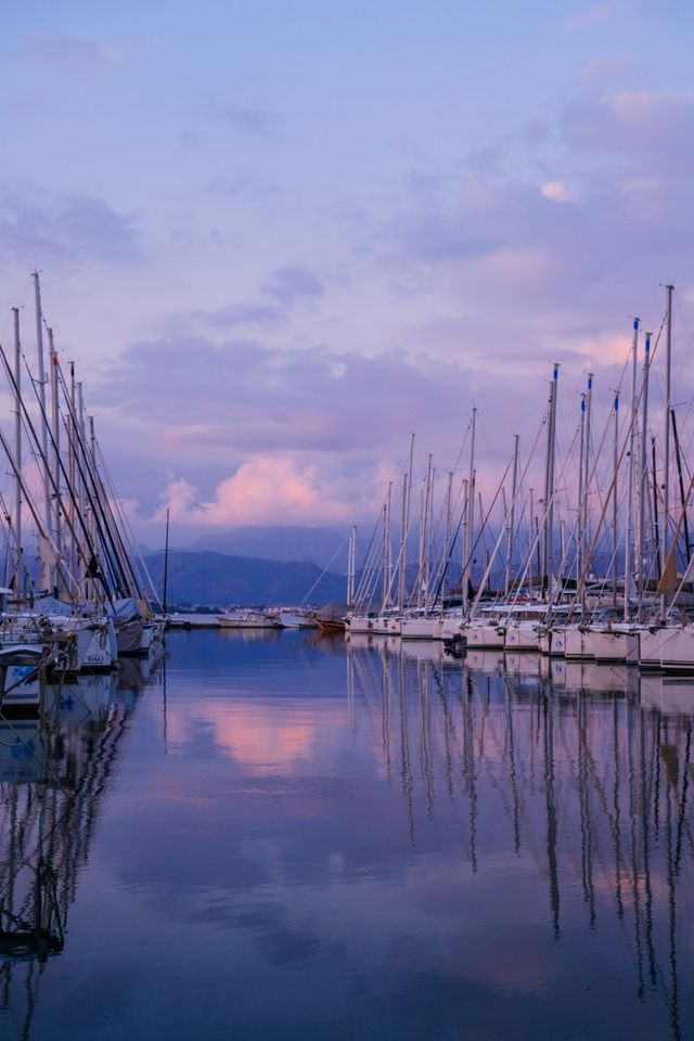 Sailboats and masts reflected in a marina beneath a lavender evening sky