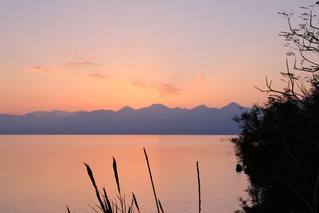 Peach sunset over calm water and distant mountain silhouettes near Antalya