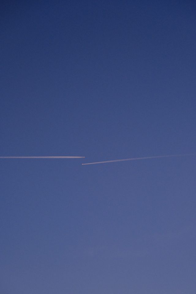 Parallel aircraft trails cutting across a dark blue twilight sky