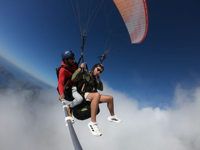 Tandem paragliders gliding along the edge of a bright cloud