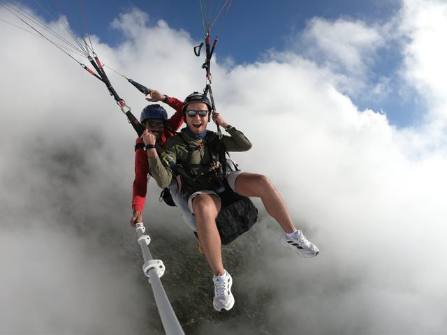 Tandem pair flying through broken white cloud