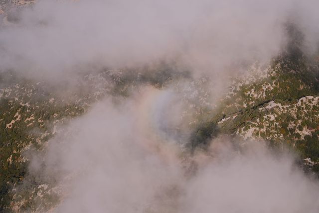 Rocky mountainside appearing through a gap in the cloud