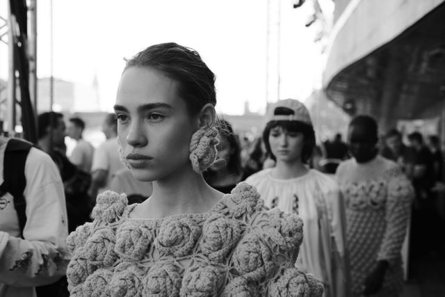 Close black-and-white view of a model wearing large flower-shaped appliqués around the neckline.