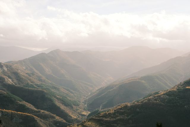 Panoramic view of wooded mountain ridges receding into soft golden light.