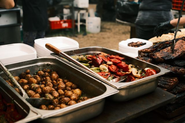 Serving trays hold cooked mushrooms and colourful grilled vegetables beside the barbecue.