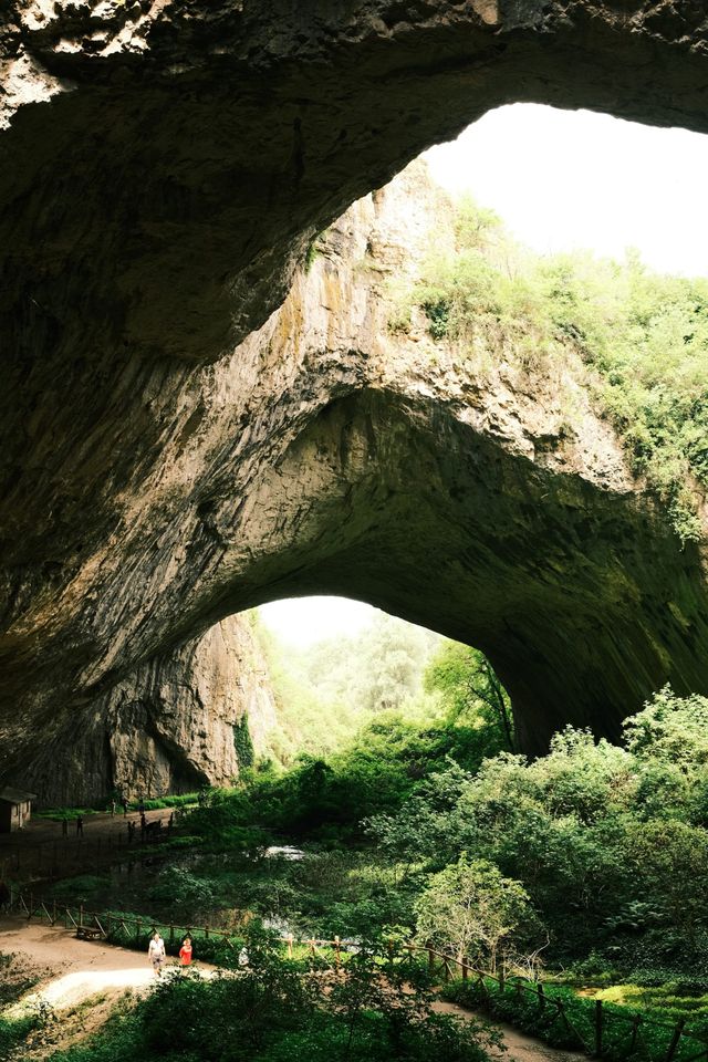 Natural stone arches and green floor inside Devetashka Cave