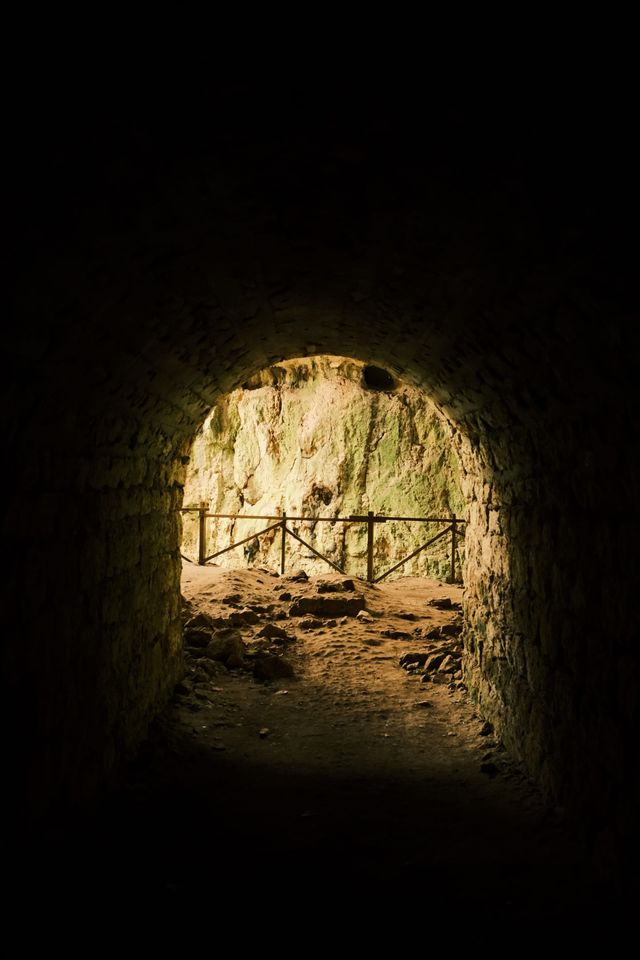 Round tunnel opening toward a railing in the darkness
