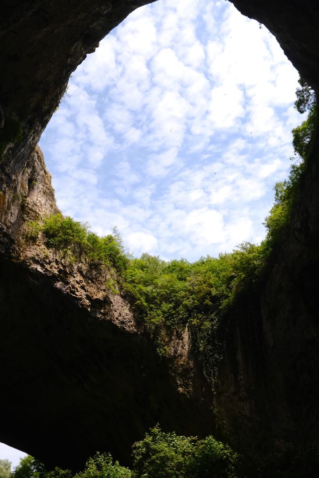 Blue sky and clouds visible through a cave skylight