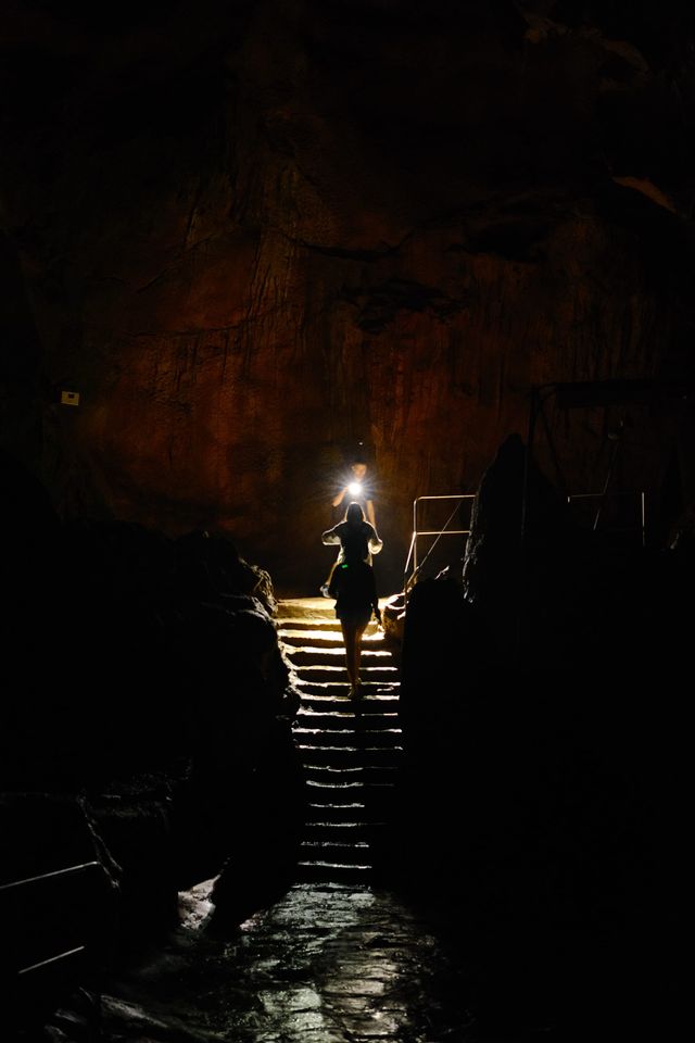 Visitor climbing illuminated steps through a dark cave hall