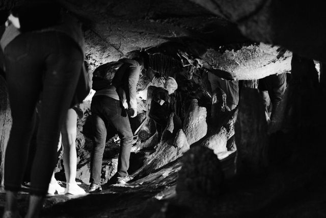 Tour group bending through a low tunnel in Ledenika Cave