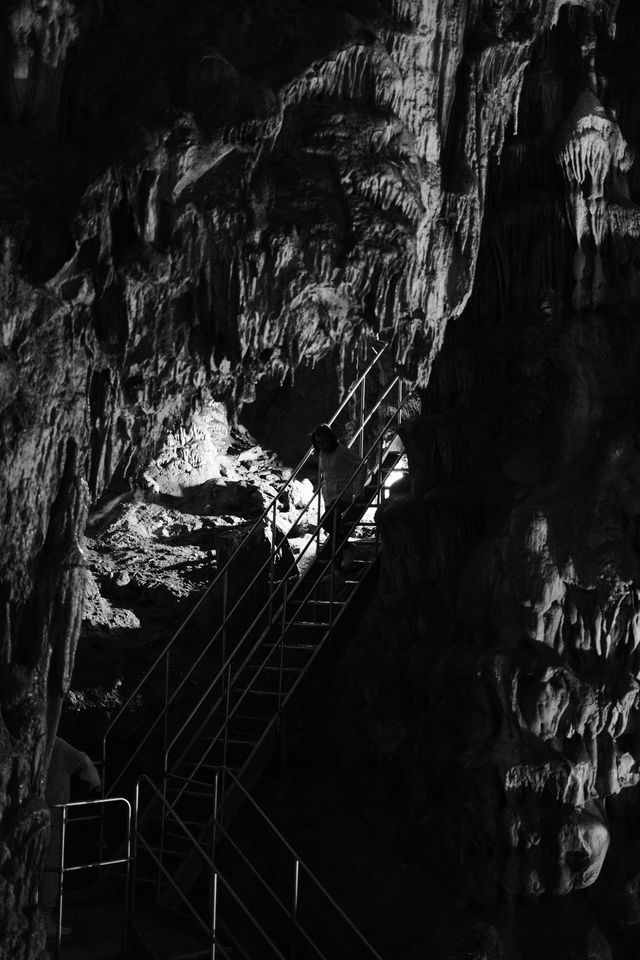 Illuminated cave formations surrounding a metal staircase