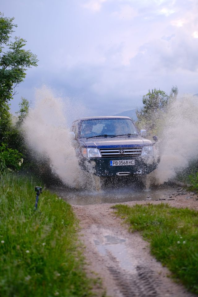 Front view of the vehicle emerging through a wall of spray
