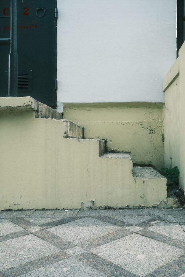 A short concrete staircase rises beside a pale yellow wall above patterned pavement in Moscow.
