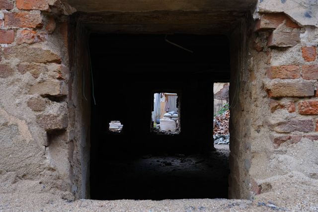 Rectangular openings line up through a dark ruined interior behind a rough brick window frame in Moscow.
