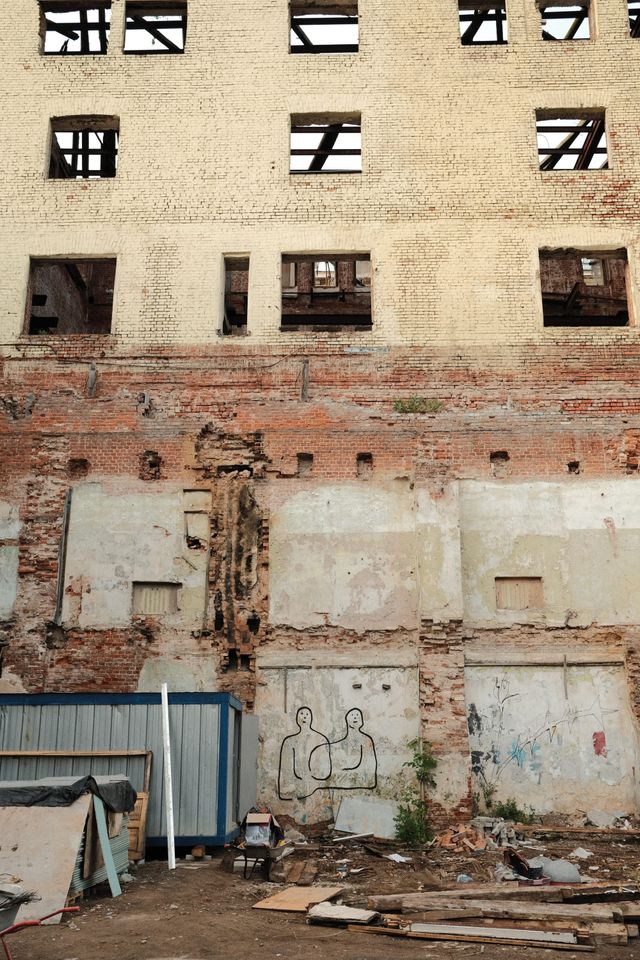 Empty windows, exposed brick and crumbling plaster cover a disused building above rubble in a Moscow courtyard.